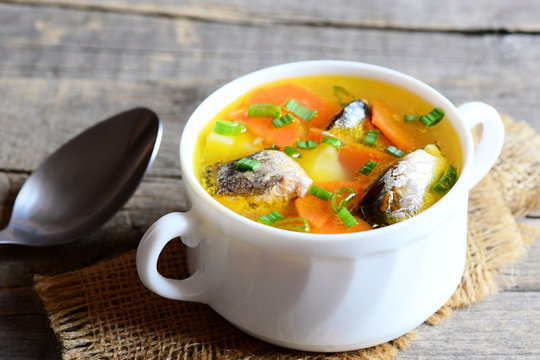 Healthy and nutritious fish soup. Slow cooked hearty fish soup with vegetables in a bowl. Vintage wooden background. Closeup