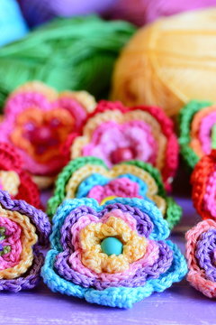 Crochet multi-colored flowers set. Crochet flower motifs and patterns. Interesting hobby for women and children. Closeup. Vertical photo