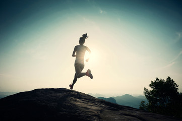 successful young woman running on sunrise mountain peak