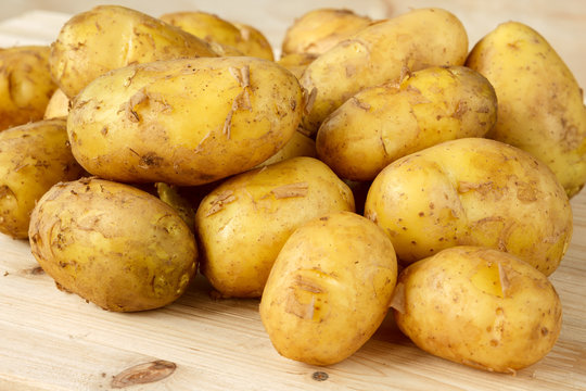 Raw new potatoes with peeling on a wooden background