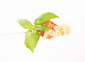 Risotto with tomato and pea on a fork on a white background