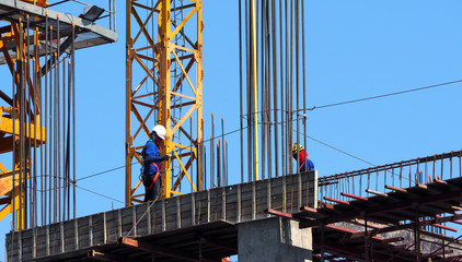 Construction site and labor working on high building.