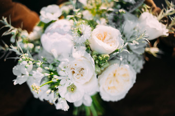 a beautiful bridesmaid bouquet of white flowers lying on a brown easy chair