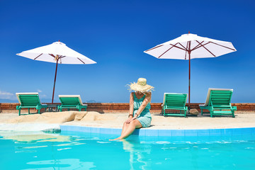  Woman relaxing near poolside on resort - Powered by Adobe