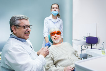 Stomatologist and patient smiling. Elderly male at dentist office. Experienced professionals guarding your health.