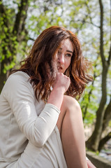 Young beautiful girl sits sad in a white dress in a street in the spring city of Lviv