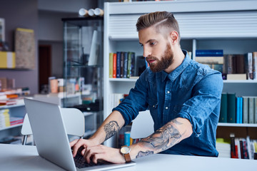Hipster, designer working on laptop in office