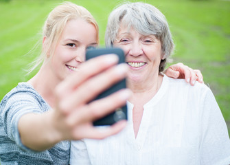 Young and old woman taking a picture with smart phone