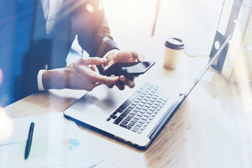 Fototapeta premium Businessman holding modern smartphone on hands.Coworker working at sunny office at work place.Visual effects.Blurred background.