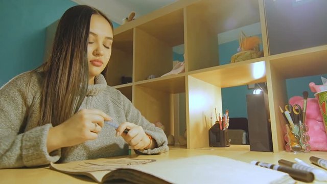 A young woman with long hair draws a felt-tipper in the evening in the album.