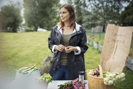 Mid adult woman standing by freshly harvested vegetables on table at urban garden