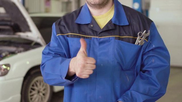 Conceptual portrait of car mechanic crossing hands with wrench