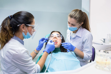 Patient with two dental doctors. Procedure at dentist office. Therapy and treatment of teeth.