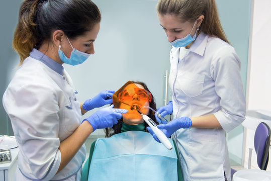 Dental doctor using curing light. Woman at dentist office. Effective methods of teeth treatment.