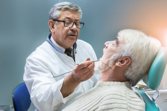 Old Man At The Dentist. Dental Doctor Is Examining Patient. Deep Knowledge Of Dentistry.