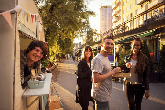 Portrait of happy customers and food truck owner on street