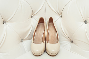 bride's biege shoes on heel on a leather vintage sofa