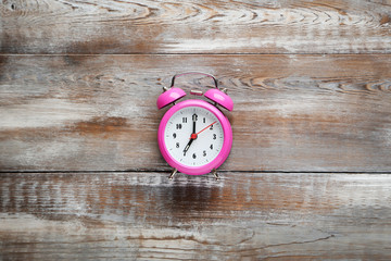 Pink alarm clock on brown wooden table