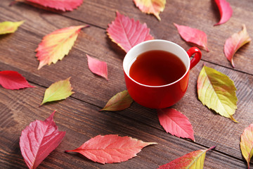 Autumn leafs with cup of tea on brown wooden table