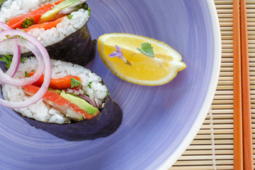 Sandwich in the style of sushi cut into half on a purple plate. Ready-made dish of Japanese cuisine from rice, salmon, avocado with vassabi sauce.