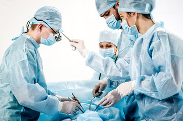 The operating nurse wipes the forehead of the surgeon during the operation.