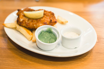 Mashed peas and sauce on plate with fish and chips.