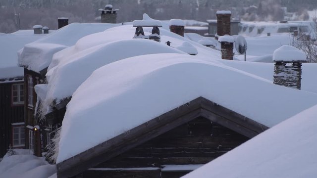 Roofs of old wooden houses covered with a thick layer of snow with smoking chimneys