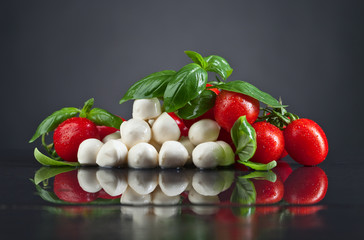 Mozzarella cheese with basil and tomatoes on black table