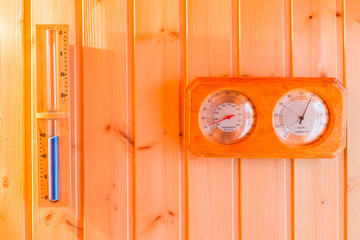 Bath thermometer, hourglass decorated on interior wooden wall of private sauna room.