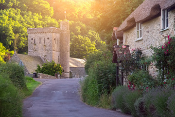 The road to the village of Branscombe. The old typical two-story Devonian house with a thatched...
