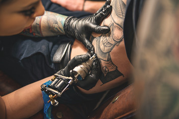 Fototapeta na wymiar Female doing tattoo on belly of man