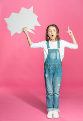 Adorable little girl holding blank speech bubble and pointing up with finger