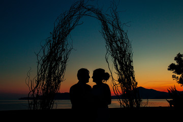 Fototapeta na wymiar Silhouette of a newlywed couple on the background of the setting sun on the sea in Montenegro.