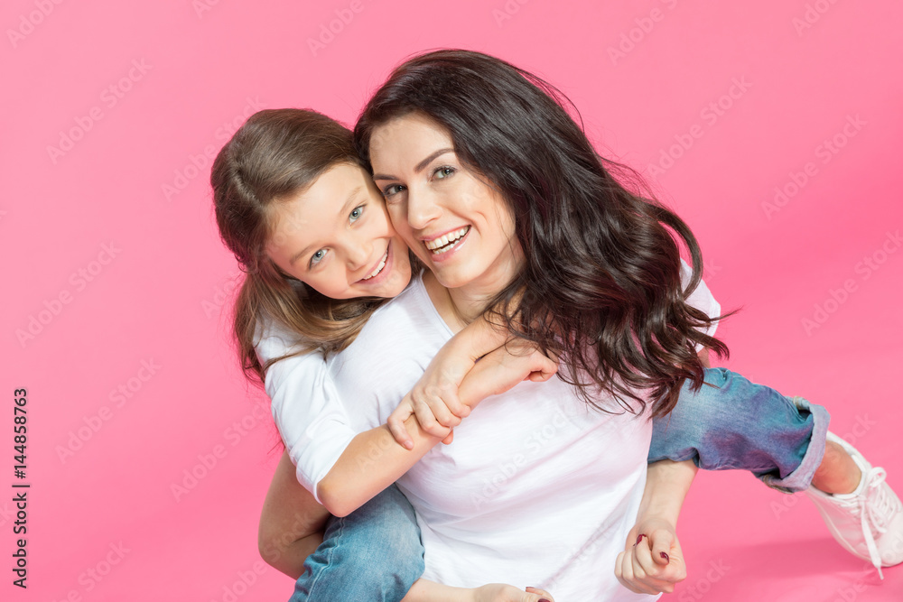 Wall mural Happy beautiful mother and daughter hugging and smiling at camera