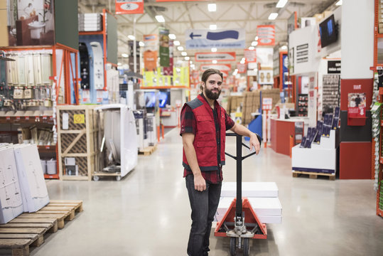 Portrait of salesman standing by handtruck in hardware store