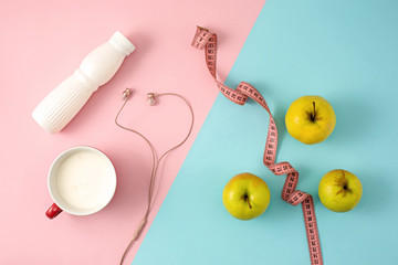 Fototapeta na wymiar The green apple and bottle of yogurt with measure tape