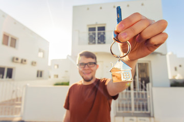 Concept of housewarming, real estate, new home - Young man holding key of new house.