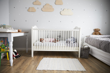 Side View Of Baby Girl Sleeping In Nursery Cot