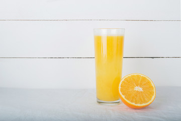 Fresh oranges juice in glass and fruit on white wooden background. Selective focus. Wellness setting. Health concept.