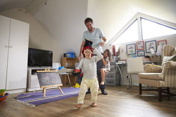 Father Having Game Of Tag With Children In Playroom