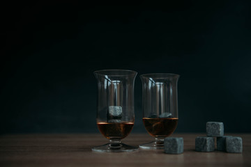 Stones for cooling whiskey and glases tulup on dark wooden background
