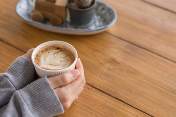 Woman hands holding hot cup of coffee or tea in morning sunlight,emale hands holding cups of coffee on rustic wooden table background