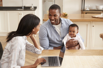 Mother Works From Home As Father Holds Baby Daughter