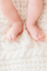 Baby's feet on white knitted background. Little child's bare feet. Cozy morning bedtime at home. Place for text.