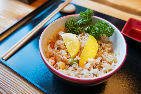 Asian cuisine - Tori tyahan. Fried rice with chicken meat, vegetables and radishes in bowl.