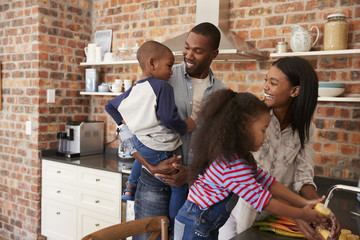 Children Helping Parents To Prepare Meal In Kitchen