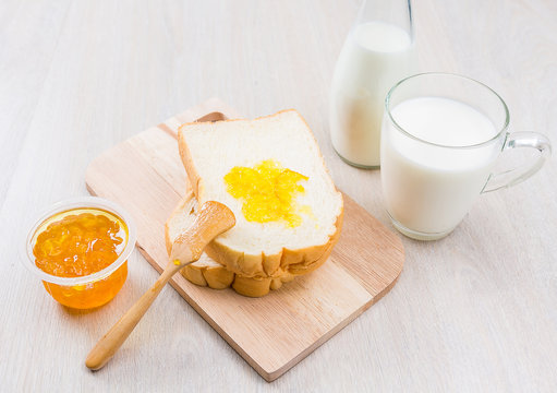 Breakfast with milk, bread and jam on the wooden table