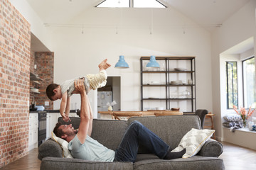 Father And Son Having Fun Playing On Sofa Together