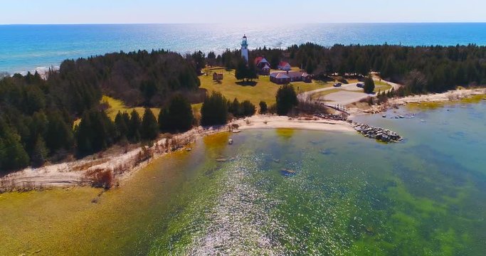 Scenic Lighthouse stands tall on rocky peninsula, breathtaking aerial view.
