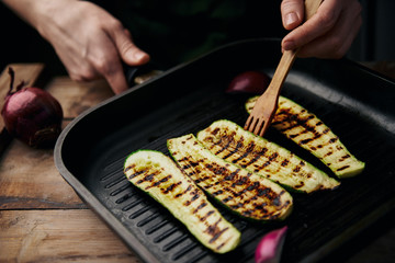 Close-up of female cooking zucchini on grill. 